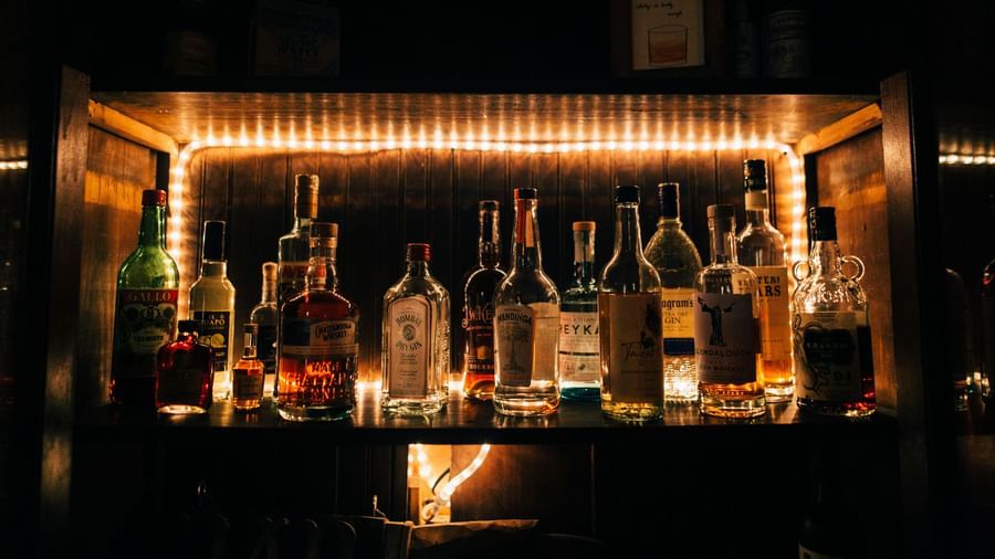 A dimly lit bar area with various bottles of spirits prominently displayed on illuminated shelves.