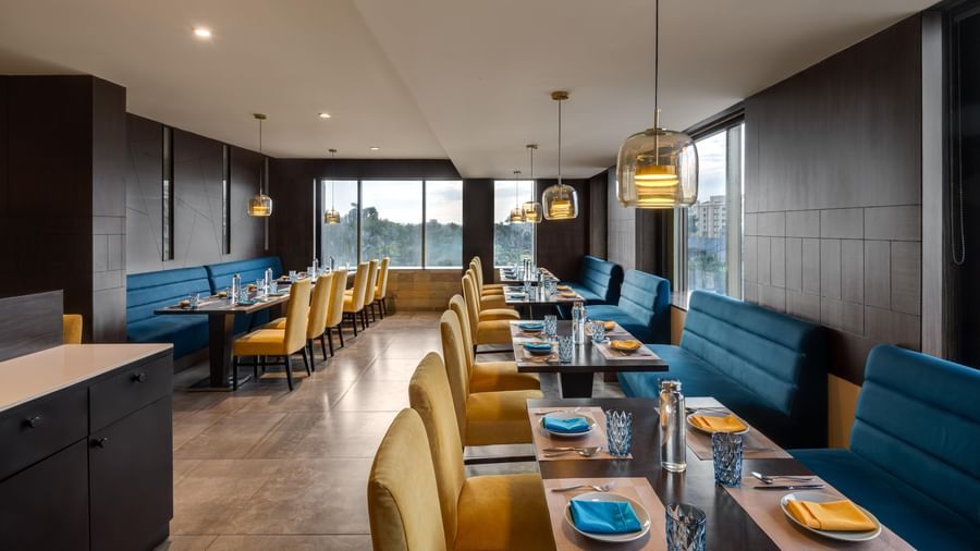 Restaurant interior at Voyage Milestone Hotel and Banquet with blue seating and warm lighting.