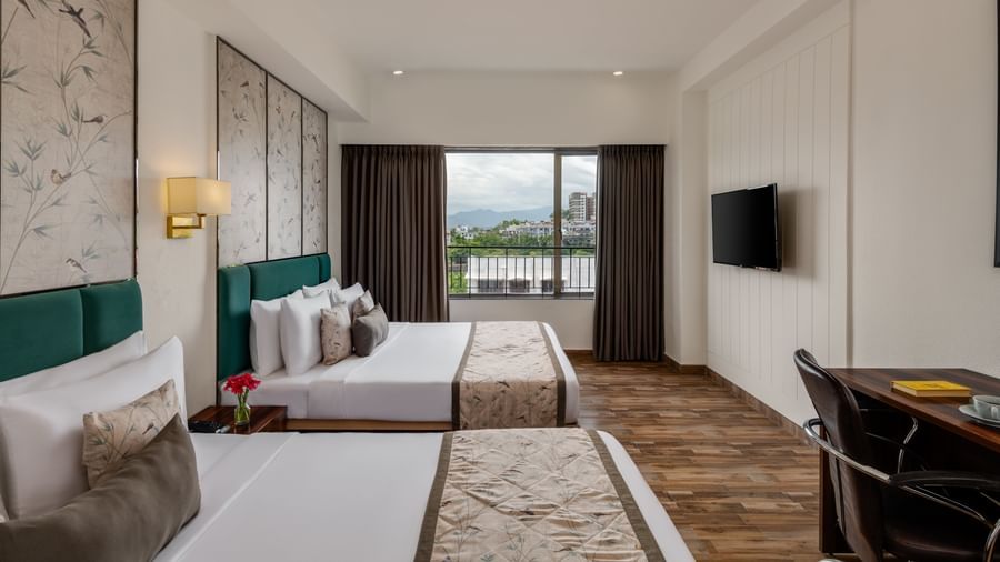 Bright guest room at Voyage Milestone Hotel and Banquet with twin beds and balcony view.