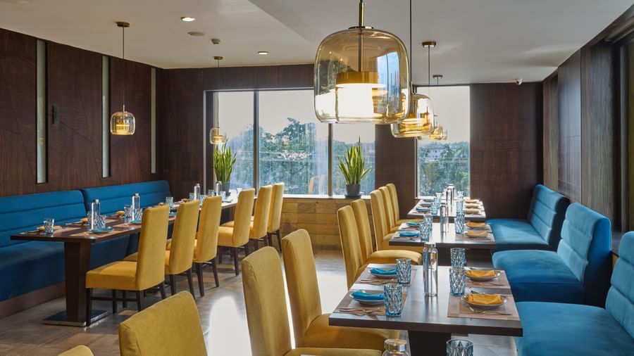 Bright dining area at Voyage Milestone Hotel and Banquet with modern furniture and large windows.