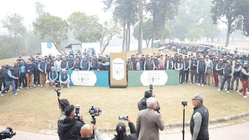 A large group gathered together with a golf celebration board on the golf course 