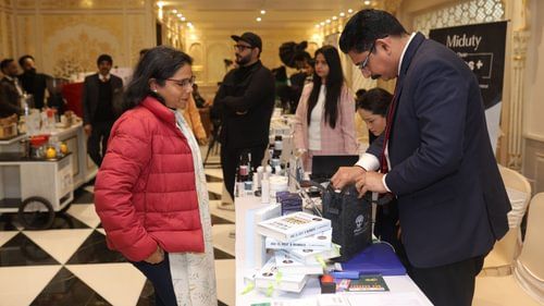 An image of people standing near a table where a lot of items are placed including books, some boxes, and  bags at Heritage Village Resorts & Spa