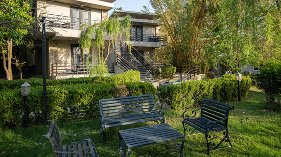 Lawn area of the resort building with a lush green garden and outdoor seating in the daytime at The Golden Tusk, Jim Corbett