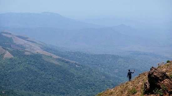 A person standing on top of Mulayanagiri hills while looking at the valley below