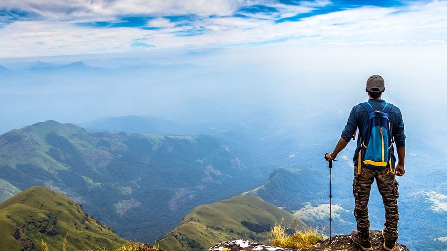 A man standing a top of a hill with panoramic views in sight during daytime