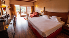 An image of a bedroom featuring a double size bed, a sofa , work desk and chair, and a cabinet table  at The Carlton, Kodaikanal