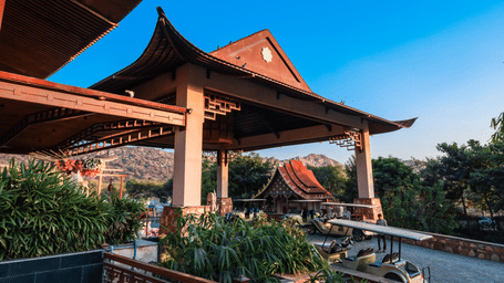 The exterior entrance of Ananta Spa & Resort, Jaipur, showcases its distinctive pagoda-style architecture against a bright blue sky.