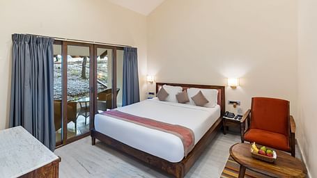 image of the bedroom at the luxury family suite featuring a plush king size bed with huge french windows besides it adorned with blue drapes at aranya vilas in udairpur