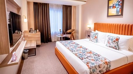Superior Room at ASTER GRAND BY ZENQ SAKET with a bed, bed side table, TV, a chair and a window with curtain in the background.