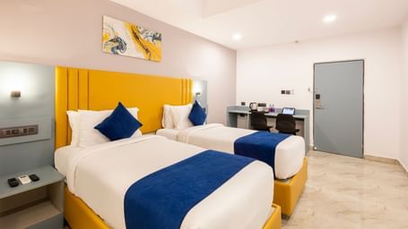 Full view of Superior Room featuring a bed with blue and white bedding, a yellow headboard, and modern furnishings including a desk and TV - Beestay Hotel Financial District, Hyderabad