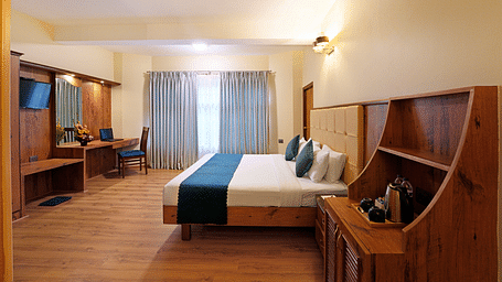 An Executive Room featuring a queen size bed, wooden decor and large windows - Cross Roads Inn, Bengaluru
