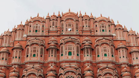 Front view of Hawa Mahal, the iconic pink sandstone palace in Jaipur, India, featuring its ornate lattice windows and intricate facade.