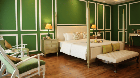A room at Dileep Kothi, Jaipur with a double bed, side tables with night lamps and green walls.
