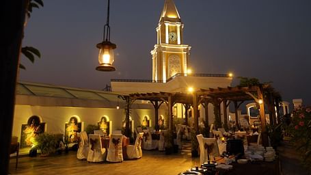 Rooftop clock tower at night, highlighted by decorative lighting against the night sky