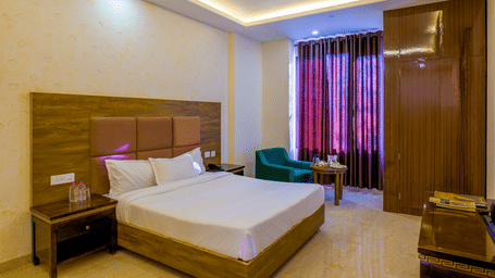 The Premium Room featuring a large bed with a padded headboard and a small seating area by a window at Grassfield Riveria Resort.