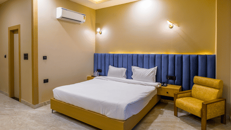 Wide-angle view of a contemporary bedroom with neutral walls, a king size bed, integrated ceiling lighting, and a wall-mounted air-conditioner – Grassfield Riviera Resort