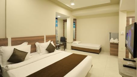 Close up of the king size bed and single bed in the Suite of Highland Resort, facing a wall-mounted TV.
