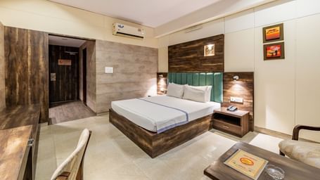 Extended view of the Maharaja Deluxe Room at Hotel Highway King, Behror, furnished with a double bed, air-conditioning, a work desk and seating area for two.