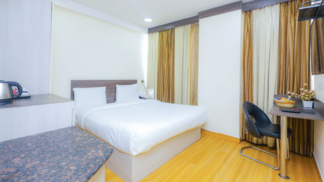 A bright hotel room featuring a bed, a desk, and large windows with privacy curtains - Hyphen Business Hotel, Noida