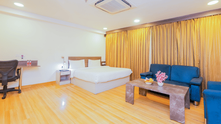View of a hotel room with a large bed, a blue sofa, and wooden flooring - Hyphen Business Hotel, Noida