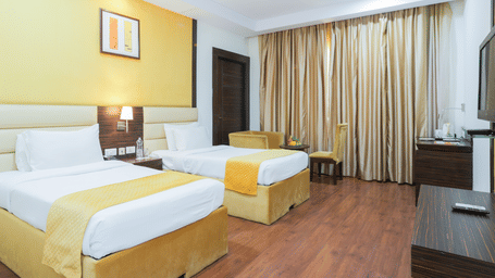 Spacious twin-bed room with wooden flooring, work desk, and ceiling-to-floor curtains at Hyphen Premier Hotel, Meerut.