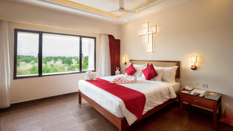 Honeymoon Suite with a plush king sized bed, bedside lamps, and a large window offering natural light and views