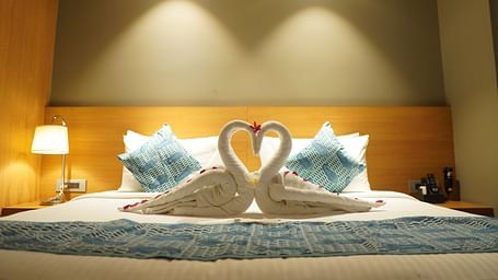 Spacious bed with towels folded into swans and warm lighting