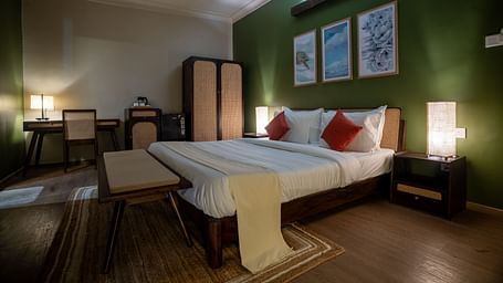 Well-lit bedroom with green accent wall, cosy furnishings, and twin beds at Kssemya.