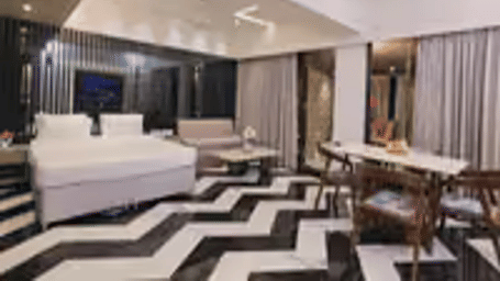 Suite at Kumar Resort by Turtle with a white bed, black slatted feature wall, chevron marble floor, sofa, dining set and ceiling fans.