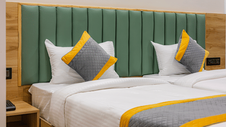 A bedroom at Lemonridge by Monday Hotels - KPHB featuring a large bed, matching runners, green headboard, and wood-paneled walls.