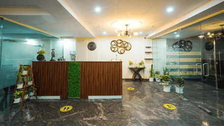 Reception area of Lime Tree Hotels & Service Apartment Private Limited featuring a green counter and a chandelier lit ceiling.