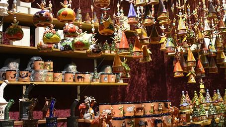 Display of colourful handcrafted pottery and hanging ceramic decorations in a vibrant store setting.