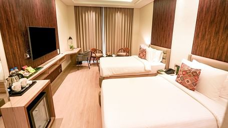 An image of a room in Bankhandi with twin beds, a minibar, a wall-mounted television and chairs - NAMAMI BY ZENQ BANKHANDI