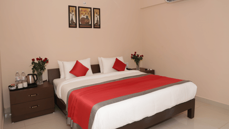 A bedroom at Nazri The Verda Hotel, Arambol, featuring a bed with cushions, bedside tables, and wall decorations.