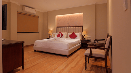Hotel room with double bed, side tables, wooden flooring, and seating area at Nirvana Gateway.