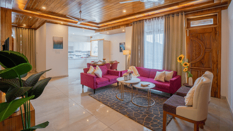 A living room area with 2 sofas, a chair, wooden ceiling, a table, indoor plants, and windows at Perfectstayz Value Paradise, Mussoorie.