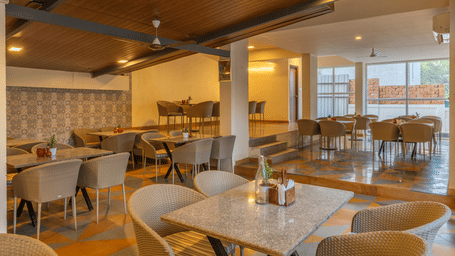 Spacious restaurant interior with wooden ceiling, set dining tables, and warm lighting at Perfectstayz Premium Carnival Suites, Marra, Goa.