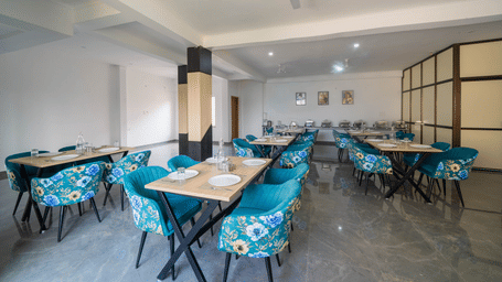 An indoor dining space with a buffet table, ceiling fan, dining tables, and chairs at Perfectstayz Premium Kaashin, Varanasi.