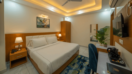 King bed with bedside tables, wall art, and study desk in guest room at Perfectstayz Premium Krishna Abode, Vrindavan.