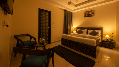 Spacious hotel room with ambient lighting and seating area - Perfectstayz Value Umra Grace, Haridwar