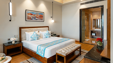 King size bed with patterned runner, bedside tables and framed artwork in the Pushkara Suite at Pushkara Resort & Spa, Ajmer