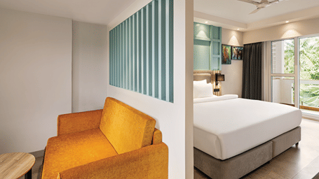 Hotel room with a king size bed, seating area and private balcony.