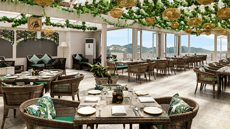 A dining terrace featuring tables, chairs, and hanging green foliage decorations at Ramada by Wyndham Mussoorie Mall Road.