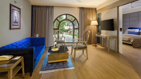 A suite with a queen size bed, a couch, a coffee table, and an arched glass doorway at Ramada by Wyndham Mussoorie Mall Road.