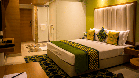 Image of a room with a bed and  pillows arranged on it  along with  a balcony | Regency Tirunelveli By GRT Hotels