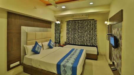 A cosy hotel room with a large bed, side tables, a television, and ample natural light - Retreat Heritage, Lonavala