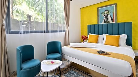 Spacious bedroom with a large window, natural light, and vibrant decor.