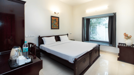 Hotel room with a double bed, a large window, and a warm wall light at Sanctum Suites Indiranagar, Bangalore.