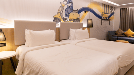 A Premium Twin Room at Sands Point Hotel, Pondicherry, featuring 2 beds with white linen and light grey headboards with reading lamps.
