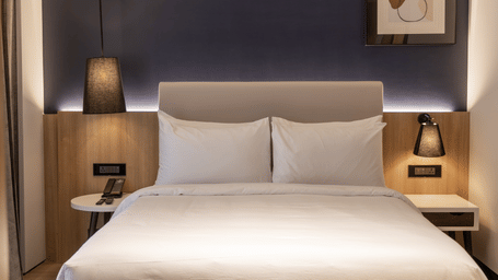 A Standard Room at Sands Point Hotel, Pondicherry, featuring a king bed with black swing arm reading lamps.